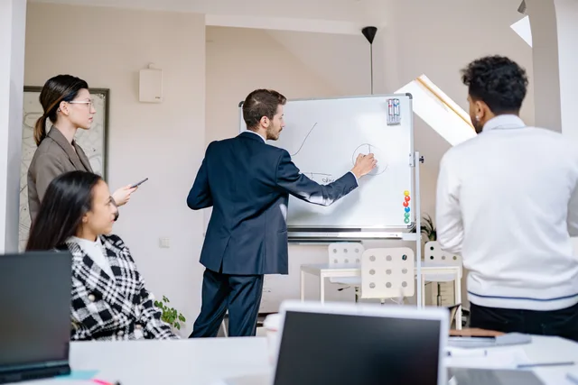 Group of business professionals engaged in a collaborative meeting with whiteboard discussions in a modern office. Mapping inputs and outputs before building an integration